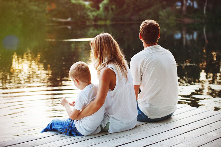 Blog - Young Family Sitting On Dock Looking Out At Lake