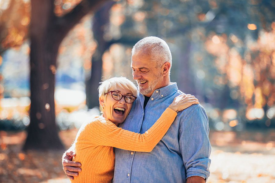 Contact - Elderly Couple Embracing While Going On Walk In The Forest